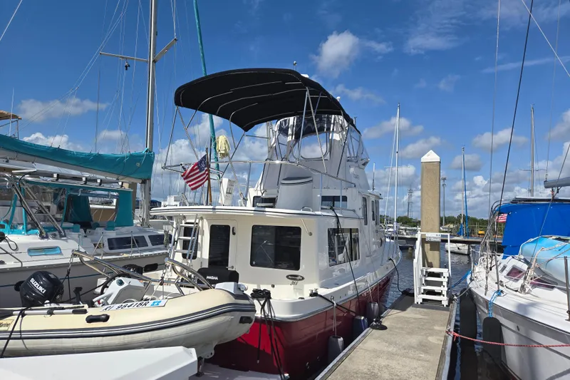 Slide: The Image of American Tug 365 Flybridge 2012 docked at marina, surrounded by sailboats under a clear blue sky. - 57