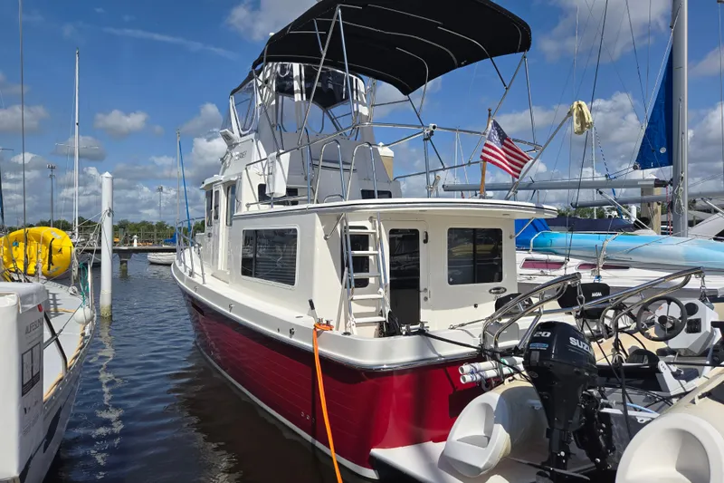 Slide: The Image of 2012 American Tug 365 Flybridge docked, featuring a red hull and flybridge under a blue sky. - 58
