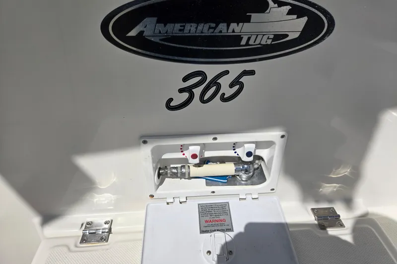 Slide: The Image of American Tug 365 Flybridge 2012, exterior detail with water hookup and logo. - 61