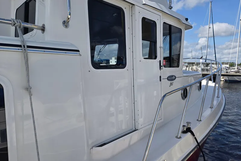 Slide: The Image of 2012 American Tug 365 Flybridge docked, showcasing sleek white exterior and railing. - 68