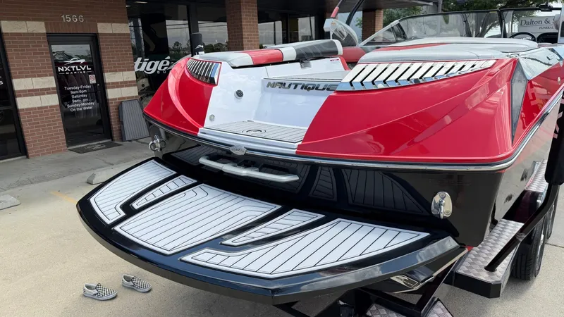 Slide: The Image of Red 2014 Nautique G25 boat on a trailer outside a store. - 3