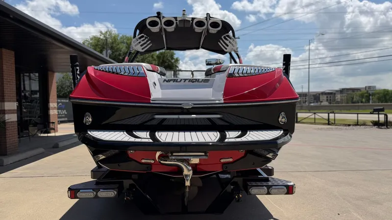Slide: The Image of Red 2014 Nautique G25 boat parked outdoors on a sunny day. - 4