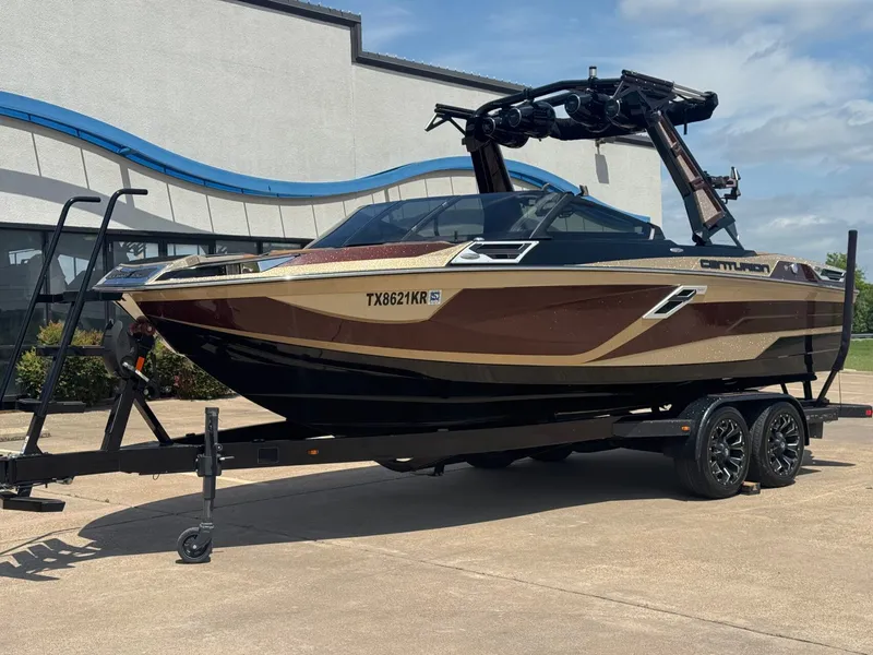 Slide: The Image of 2023 Centurion Ri230 boat on trailer in front of building. - 2