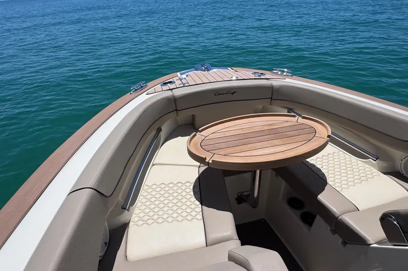 Slide: The Image of 2023 Chris-Craft Launch 25 GT boat interior with elegant seating and wooden table on water. - 16
