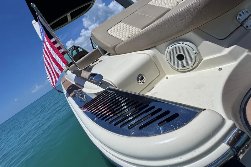 Slide: The Image of 2023 Chris-Craft Launch 25 GT boat with American flag, on calm blue water. - 29