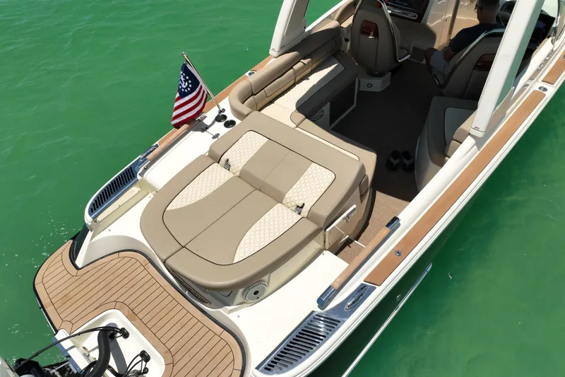 Slide: The Image of 2023 Chris-Craft Launch 25 GT boat with elegant seating and American flag on turquoise water. - 9