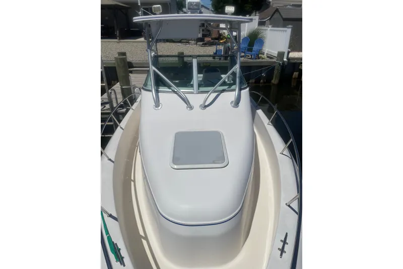 Slide: The Image of 2002 Pro-Line 260 Walkaround boat docked, featuring a sleek white deck and sturdy railings. - 6