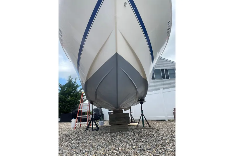 Slide: The Image of 2002 Pro-Line 260 Walkaround boat on stands, viewed from below, with a ladder nearby. - 8