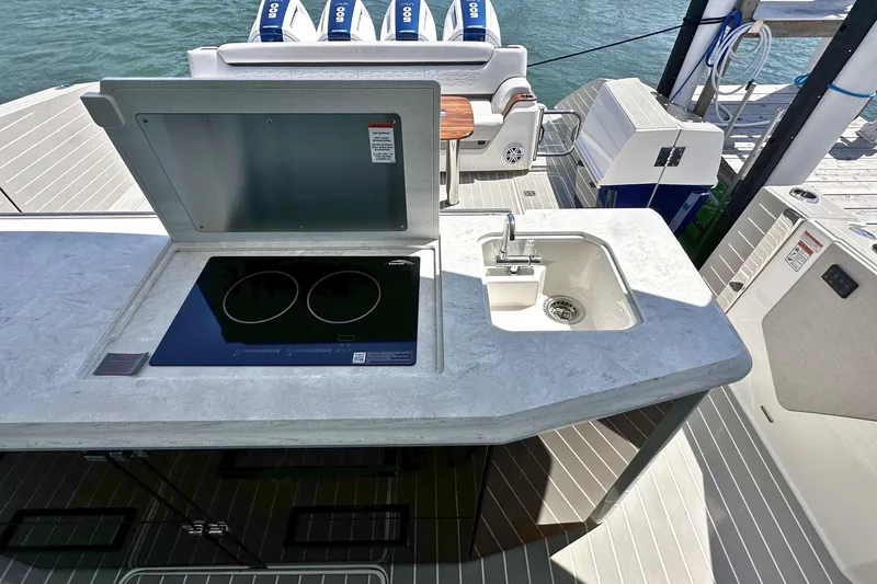 Slide: The Image of Outdoor kitchen on 2027 Tiara Yachts 56 LS with stove and sink, docked by water. - 19