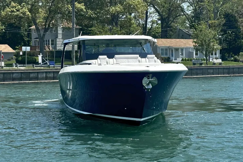 Slide: The Image of 2027 Tiara Yachts 56 LS cruising on a sunny day near waterfront homes. - 2