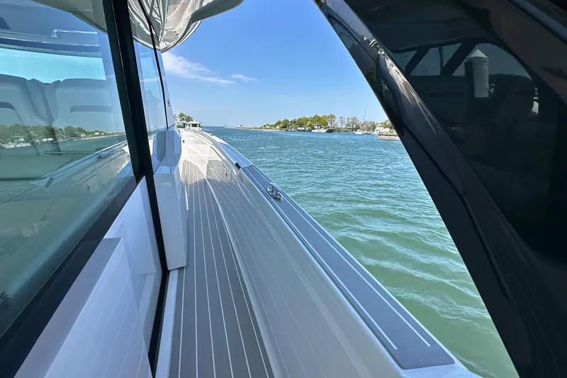 Slide: The Image of Tiara Yachts 56 LS 2027 model cruising on a serene waterway under a clear blue sky. - 32