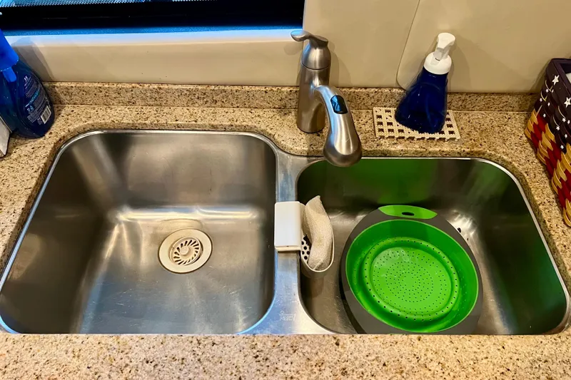 Slide: The Image of Dual kitchen sink with granite countertop, featuring a green colander and soap dispenser. - 12