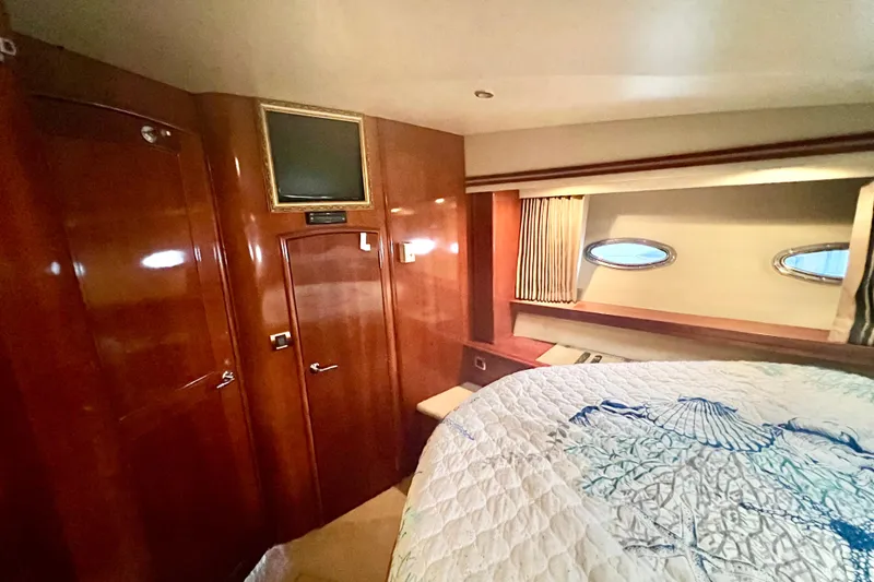 Slide: The Image of Luxurious 2005 Carver 56 Voyager yacht bedroom with elegant wood paneling and cozy bedding. - 24