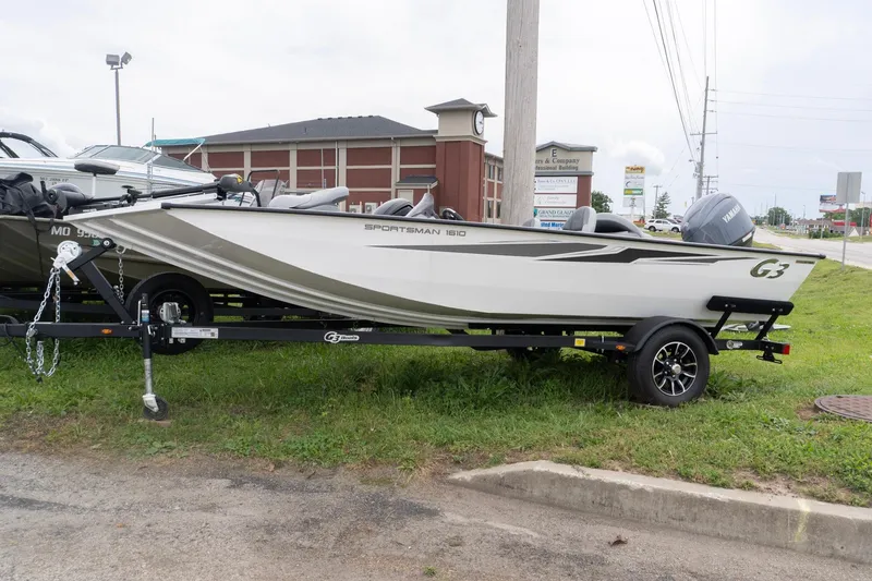 The Image of 2026 G3 Sportsman 1610 boat on trailer, parked outdoors near a commercial area. - 0