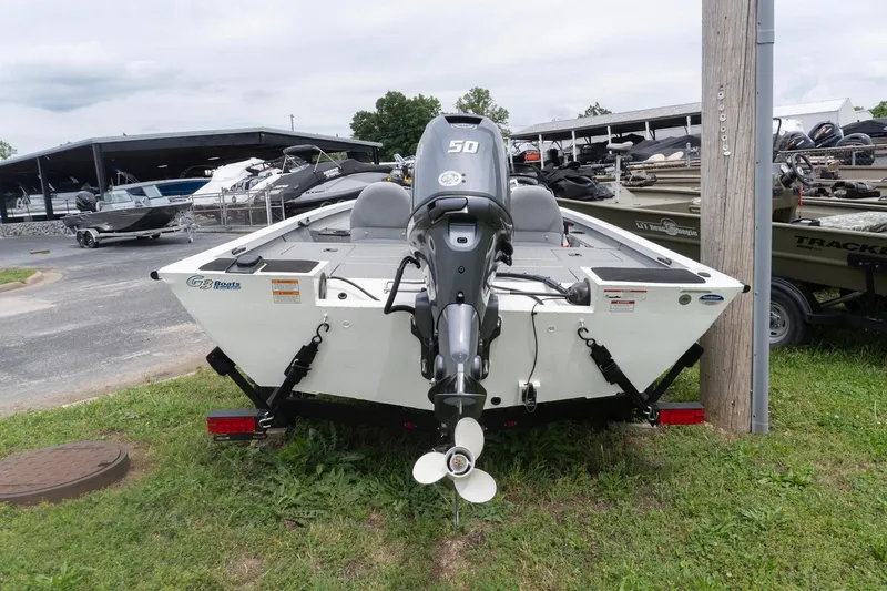 Slide: The Image of 2026 G3 Sportsman 1610 boat with outboard motor, parked on grass near a marina. - 1