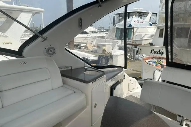 Slide: The Image of 2005 Regal 3360 Window Express yacht interior with white seating and marina view. - 13