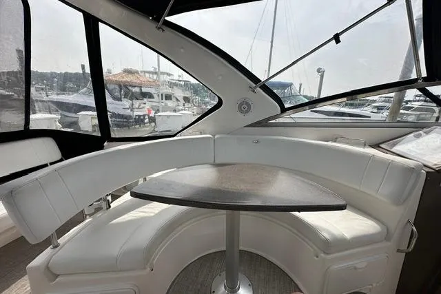 Slide: The Image of 2005 Regal 3360 Window Express yacht interior with curved seating and table in marina. - 14