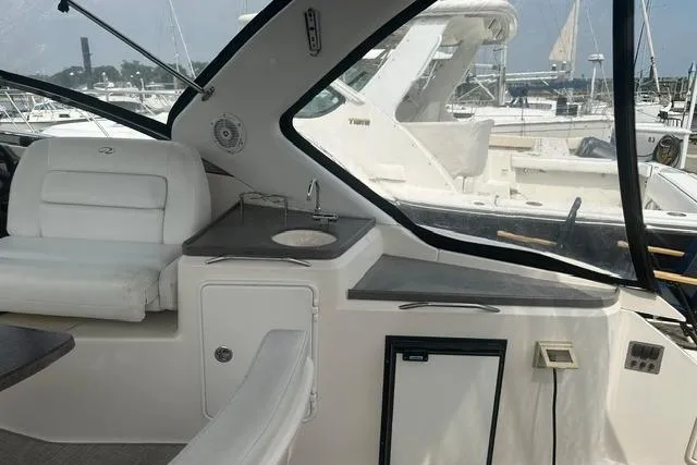 Slide: The Image of 2005 Regal 3360 Window Express yacht interior with seating and kitchenette in marina setting. - 15