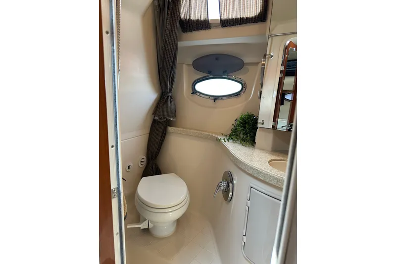 Slide: The Image of Bathroom interior of 2005 Regal 3360 Window Express yacht, featuring toilet and porthole window. - 32