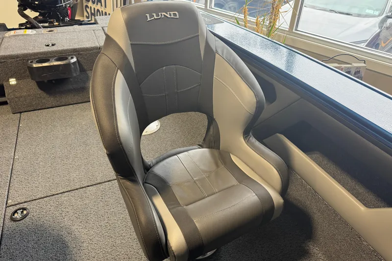Slide: The Image of 2026 Lund 1875 Crossover XS boat seat, black and gray design, in showroom setting. - 2