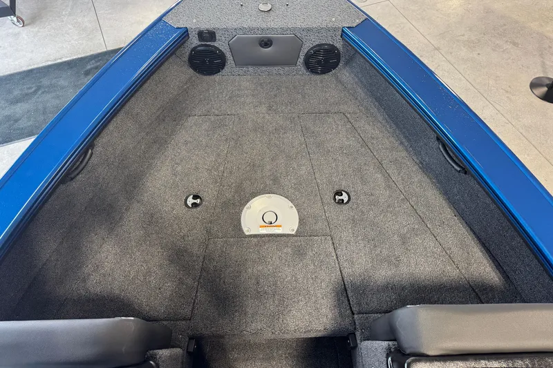 Slide: The Image of 2026 Lund 1875 Crossover XS boat interior with gray carpet and blue trim. - 9
