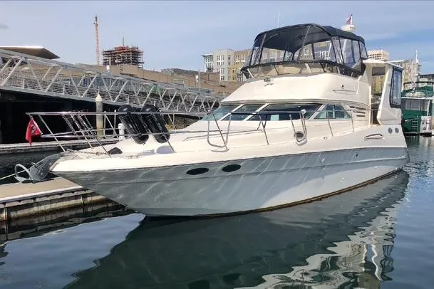 Slide: The Image of 1999 Sea Ray 420 Aft Cabin yacht docked at marina, reflecting on water. - 1