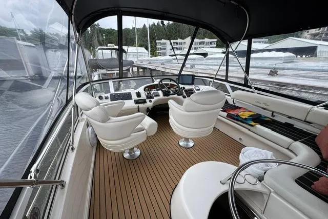 Slide: The Image of 1999 Sea Ray 420 Aft Cabin yacht interior with helm, white seating, and wood flooring. - 14