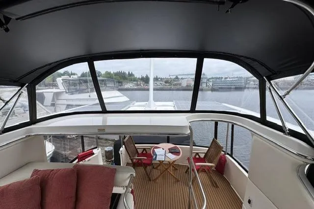 Slide: The Image of 1999 Sea Ray 420 Aft Cabin yacht interior with seating and table, overlooking marina. - 16
