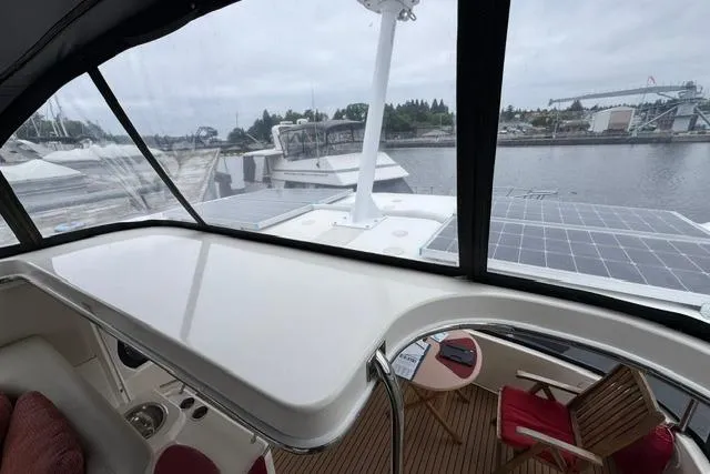 Slide: The Image of 1999 Sea Ray 420 Aft Cabin yacht interior with marina view, featuring seating and table. - 17