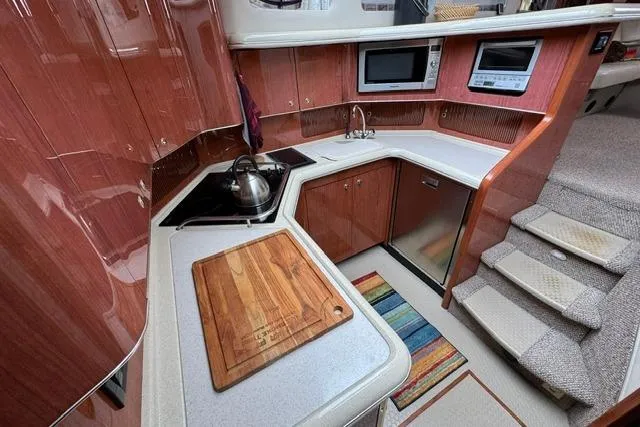 Slide: The Image of Luxurious 1999 Sea Ray 420 Aft Cabin kitchen with modern appliances and wooden cabinetry. - 32