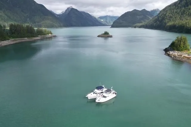 Slide: The Image of Two Sea Ray 420 Aft Cabin yachts on a serene lake surrounded by mountains. - 4
