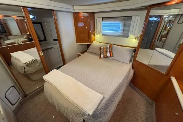 Slide: The Image of 1999 Sea Ray 420 Aft Cabin bedroom with cozy bed, wooden cabinetry, and mirrored closet. - 42