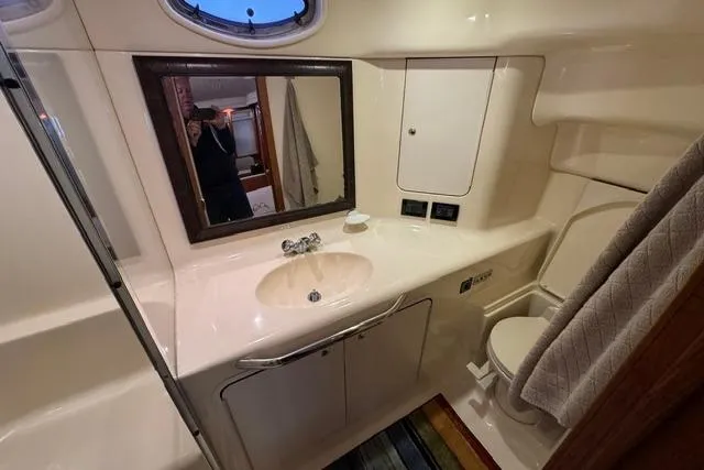 Slide: The Image of Bathroom interior of 1999 Sea Ray 420 Aft Cabin yacht, featuring sink, mirror, and toilet. - 46