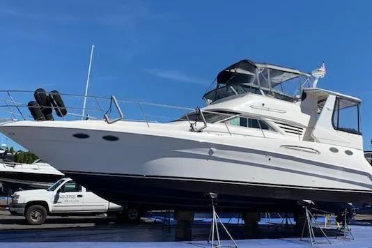 Slide: The Image of 1999 Sea Ray 420 Aft Cabin yacht on dry dock under clear blue sky. - 47