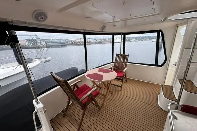 Slide: The Image of 1999 Sea Ray 420 Aft Cabin yacht interior with wooden chairs and table, overlooking marina. - 7