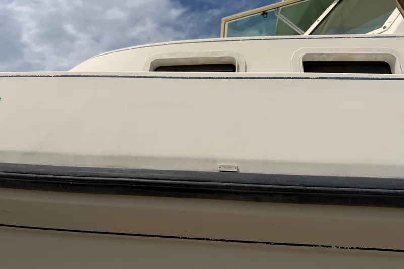 Slide: The Image of 2000 Albin 28 Tournament Express boat exterior with windows, under a cloudy sky. - 4