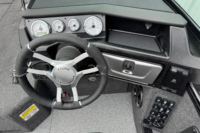 Slide: The Image of Steering wheel and dashboard of 2026 Lund 1975 Pro-V Sport boat, featuring modern gauges. - 16