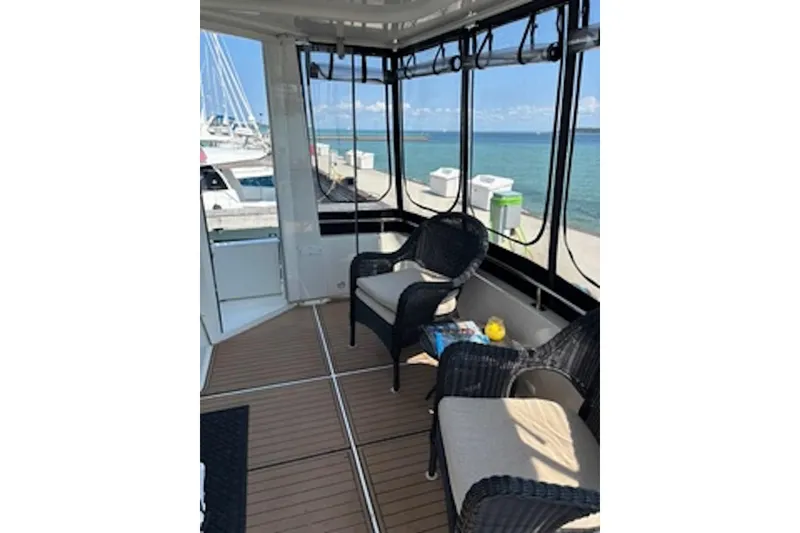 Slide: The Image of 2004 Carver 396 Motor Yacht interior with wicker chairs, docked by the ocean. - 7