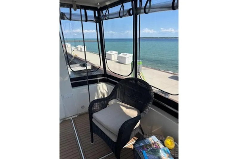 Slide: The Image of 2004 Carver 396 Motor Yacht interior with wicker chair, scenic ocean view, and reading materials. - 8