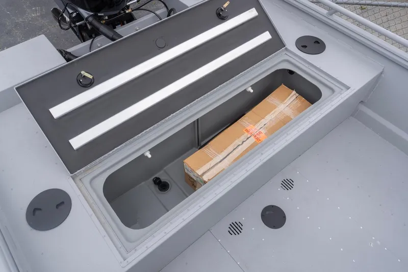 Slide: The Image of 2026 G3 Sportsman 2400 boat storage compartment with a cardboard box inside. - 18