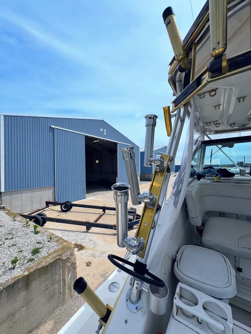 Slide: The Image of 1999 Pursuit 3400 Express boat beside blue storage shed. - 16