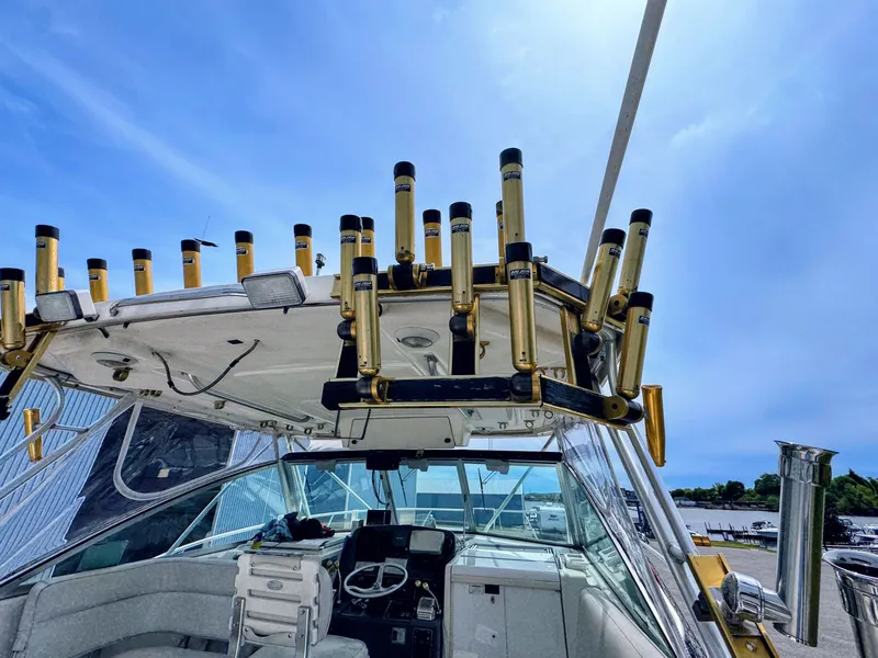 Slide: The Image of 1999 Pursuit 3400 Express boat with fishing rod holders under blue sky. - 18