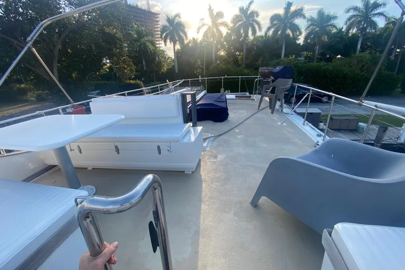 Slide: The Image of 1985 Marine Trader 50 Motor Yacht deck with seating, table, and scenic palm trees. - 4