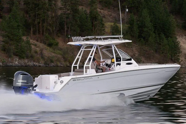 The Image of 2025 Solara 250 Center Walkaround boat cruising on a lake with forested background. - 0