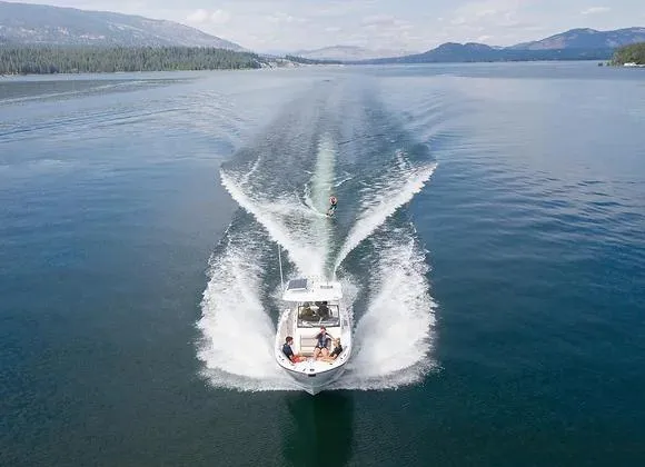Slide: The Image of 2025 Solara 250 Center Walkaround boat towing a wakeboarder on a scenic lake. - 1