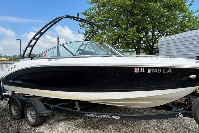 The Image of 2021 Chaparral 21 SSi boat on trailer, black and white design, parked outdoors. - 0