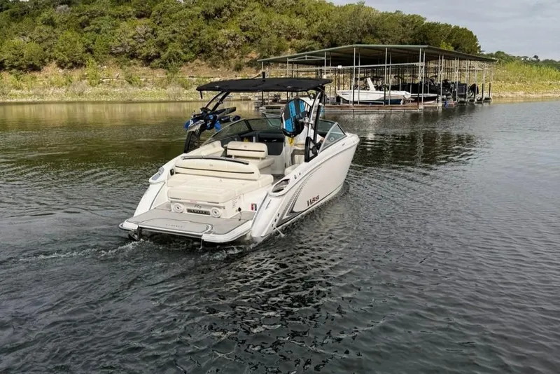 Slide: The Image of 2018 Cobalt R5 WSS Surf boat cruising on a serene lake near a dock. - 11