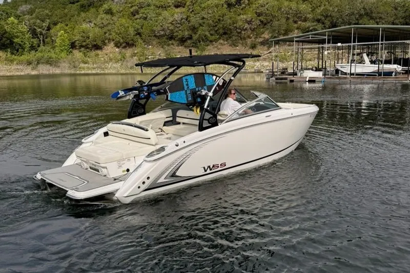 Slide: The Image of 2018 Cobalt R5 WSS Surf boat cruising on a calm lake near a dock. - 12