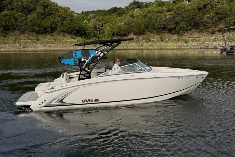 Slide: The Image of 2018 Cobalt R5 WSS Surf boat cruising on a calm lake with lush greenery. - 14