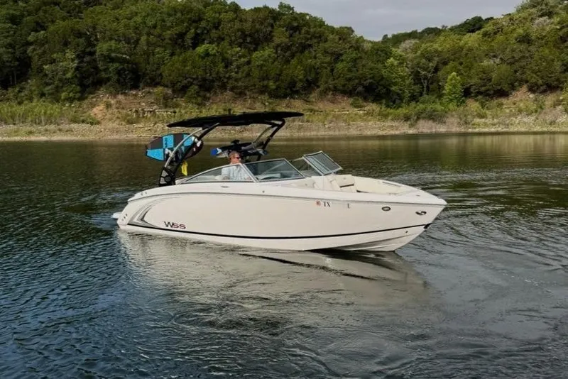 Slide: The Image of 2018 Cobalt R5 WSS Surf boat cruising on a scenic lake with lush greenery. - 16